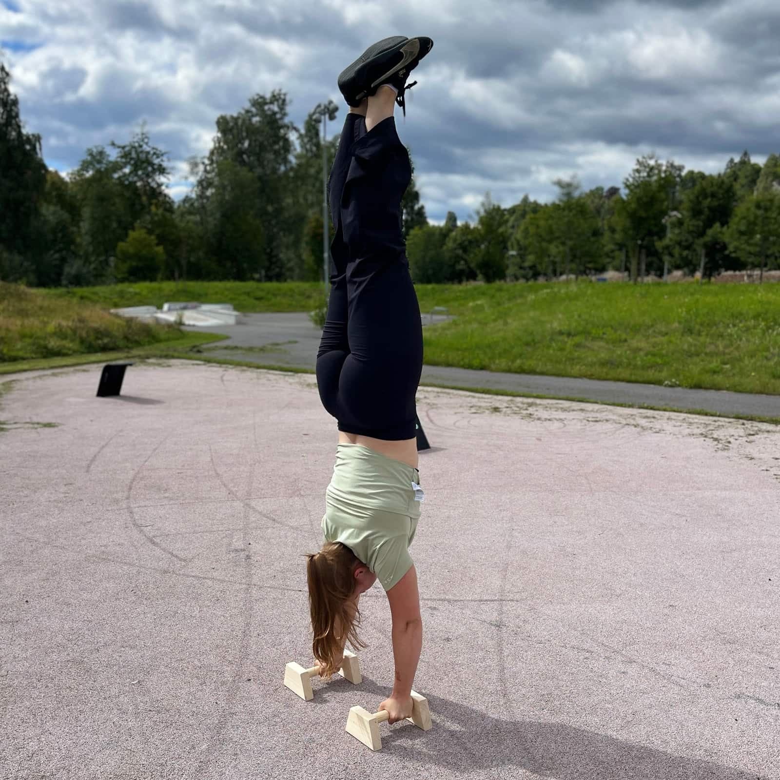 Håndstående på parallettes av tre i en park