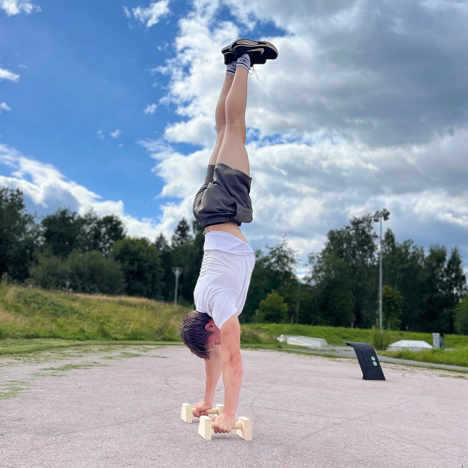 Håndstående på parallettes av tre utendørs