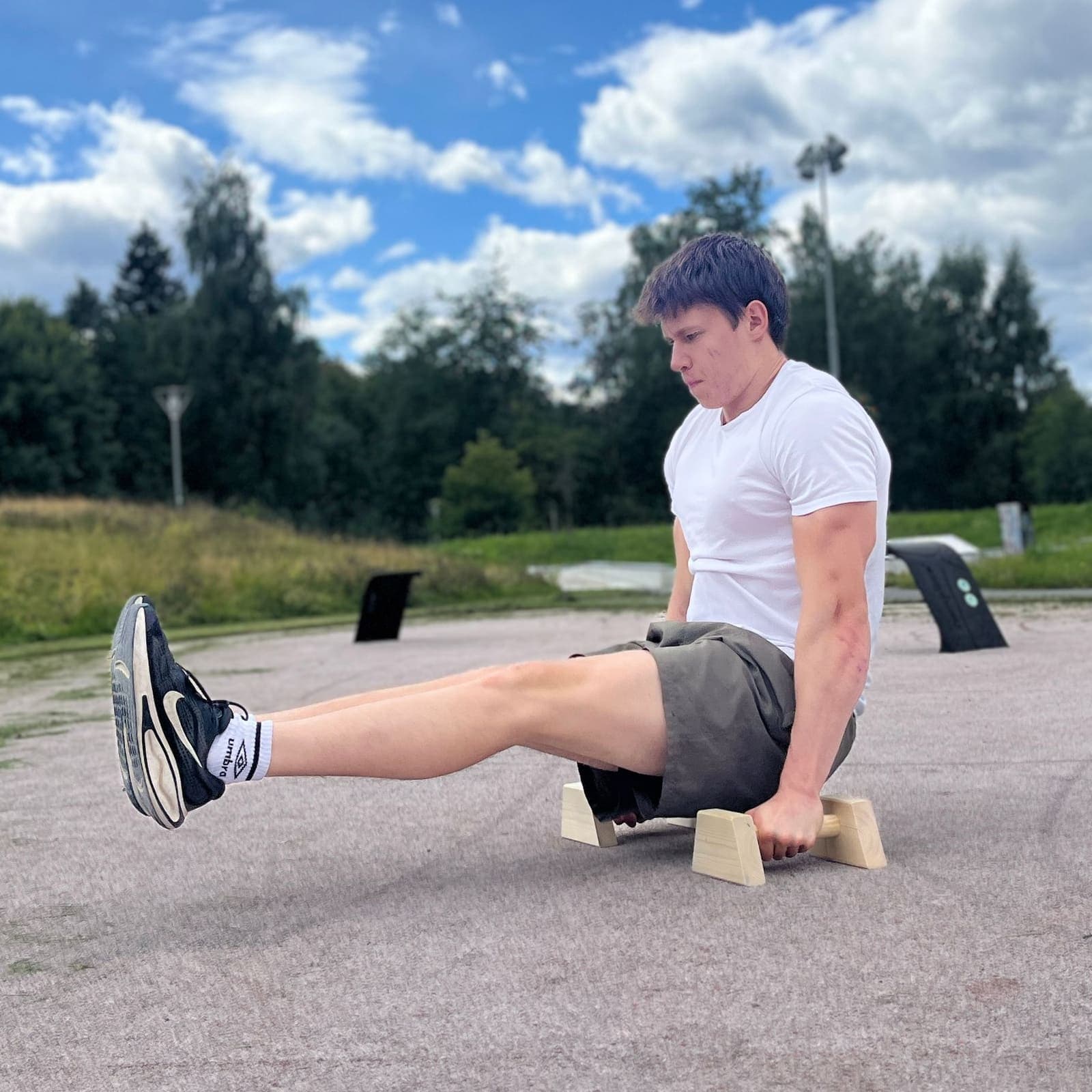 L-sit på parallettes av tre, beina rett fram